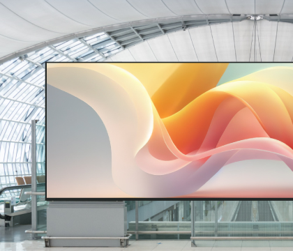 Outdoor LED video wall on a shopping mall façade with a colorful 'Welcome' graphic at sunset